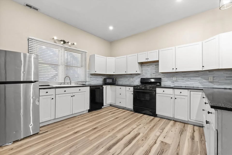 Shared kitchen with white cabinets and stainless refrigerator